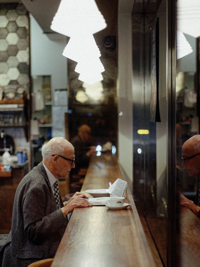 A man alone at a cafe counter, reading