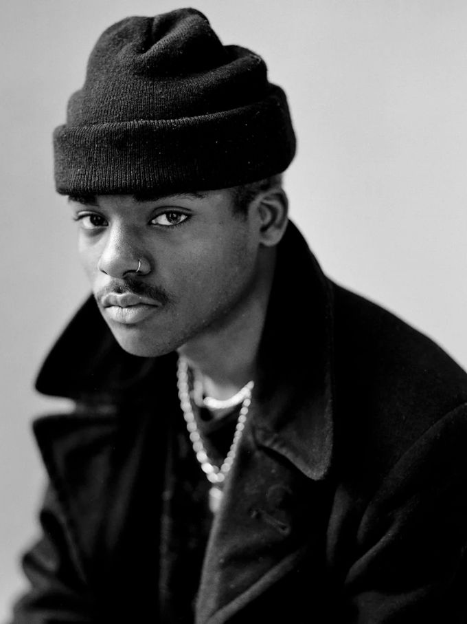 Studio portrait of a young man in a black beanie and pearl necklace